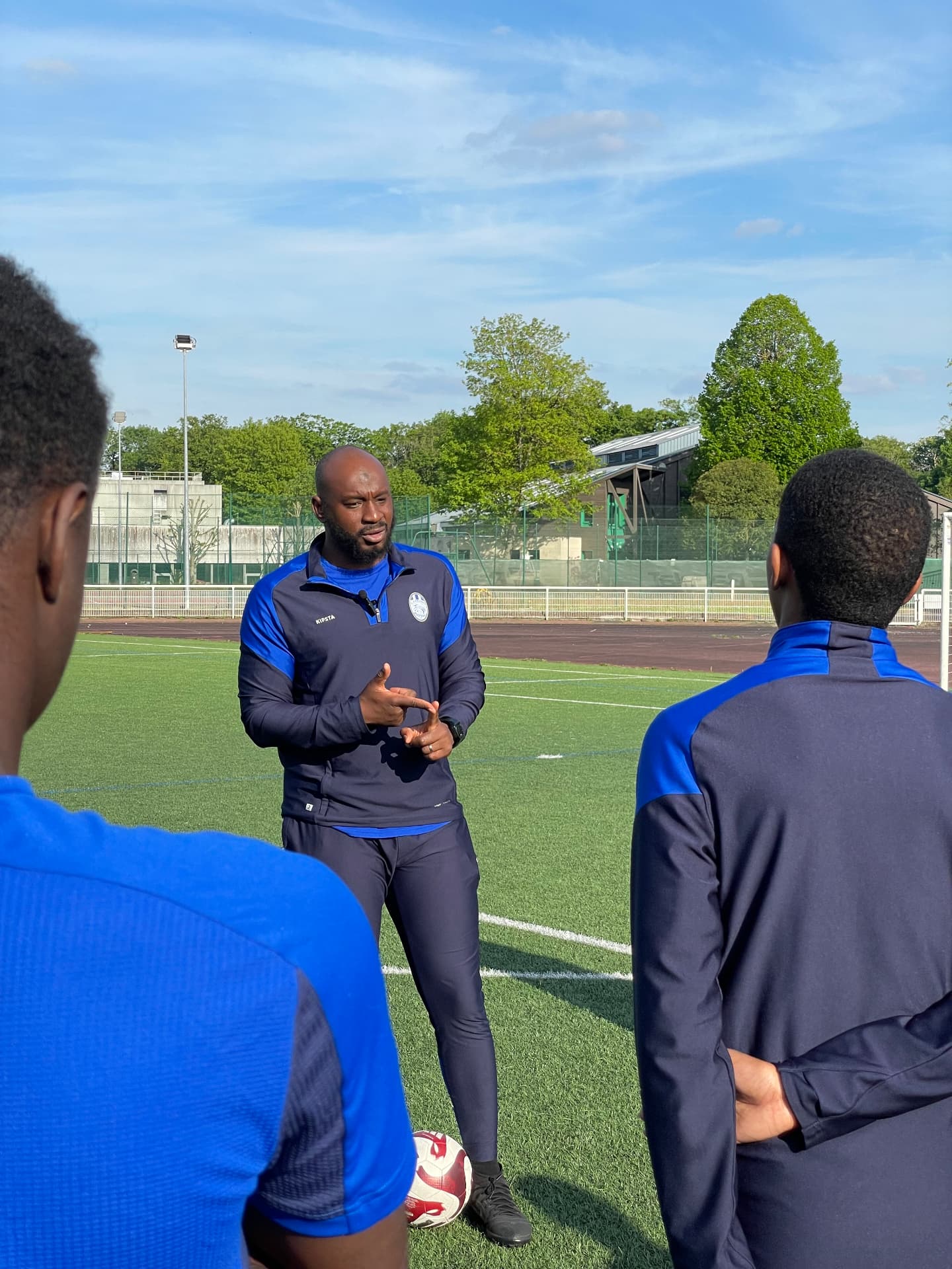 Fadhil Salou donnant des consignes à deux joueurs sur le terrain